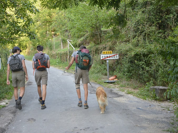 trois pèlerins sur le chemin de compostelle quittant conques